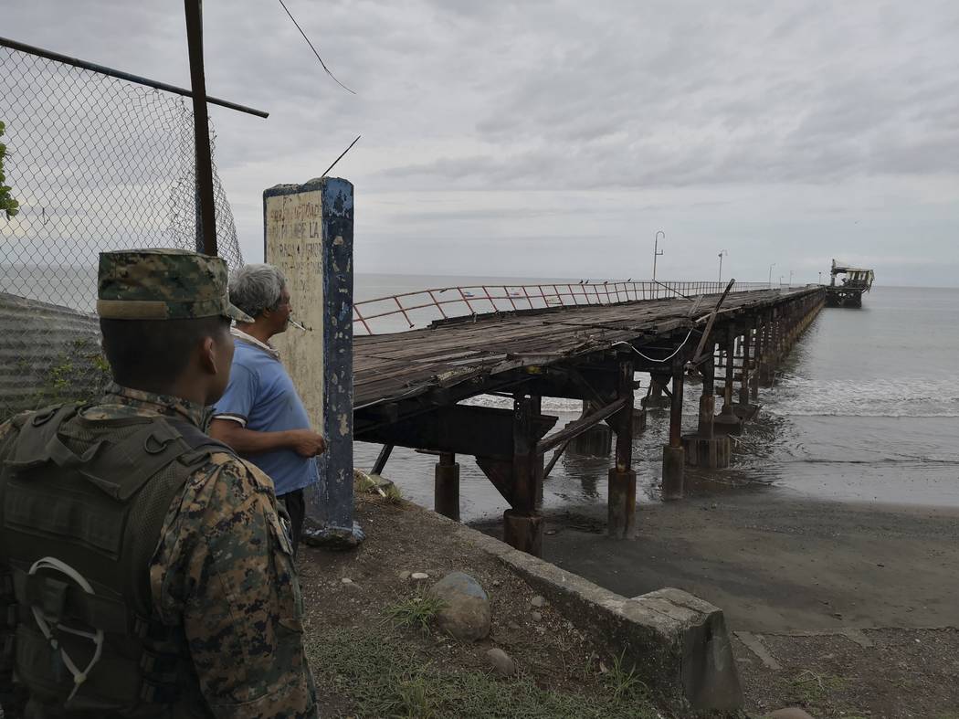 A police officer and resident look out at an abandoned pier after an earthquake made the office ...