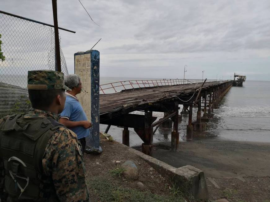 A police officer and resident look out at an abandoned pier after an earthquake made the office ...