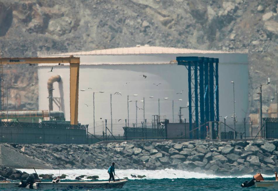 A fisherman prepares his boat near an oil storage tank in Fujairah, United Arab Emirates, Monda ...