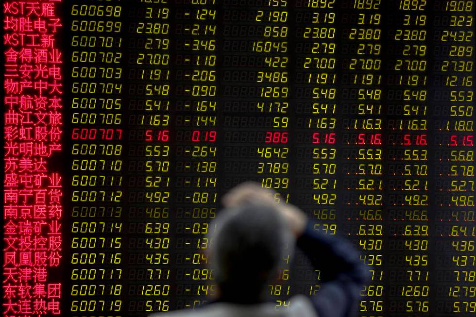 A man rubs his forehead as he monitors stock prices at a brokerage house in Beijing, Monday, Ma ...