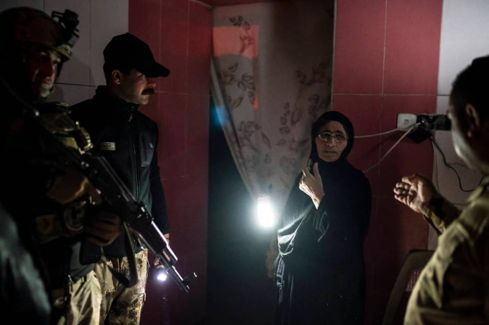 In this April 2, 2019 photo, Iraqi army 20th division soldiers talk to a woman during a nightti ...