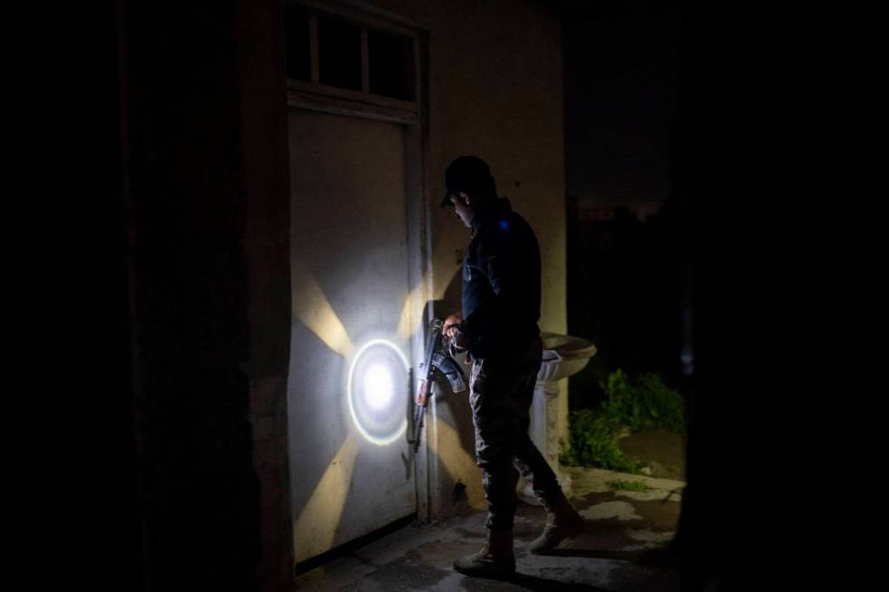 In this April 2, 2019 photo, an Iraqi army 20th division soldier uses his AK-47 rifle to knock ...