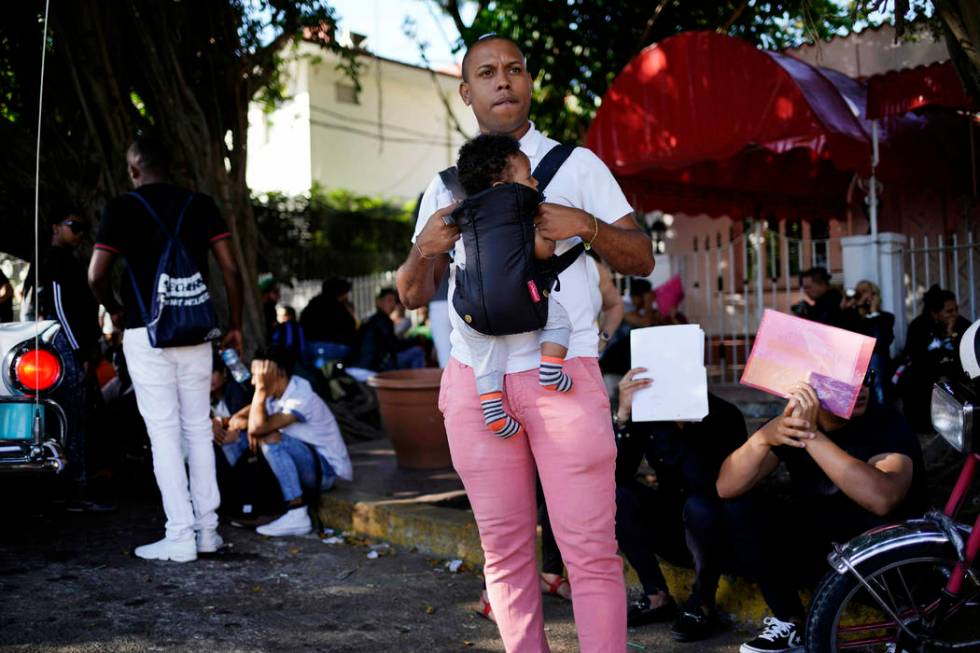 In this April 26, 2019, photo, a man holds his baby while he waits his turn to enter Nicaragua' ...