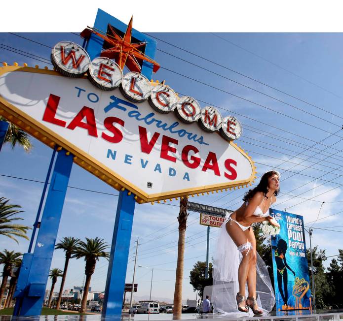 A women in a swimsuit blows a kiss to the crowd while on a temporary stage set up next to the " ...