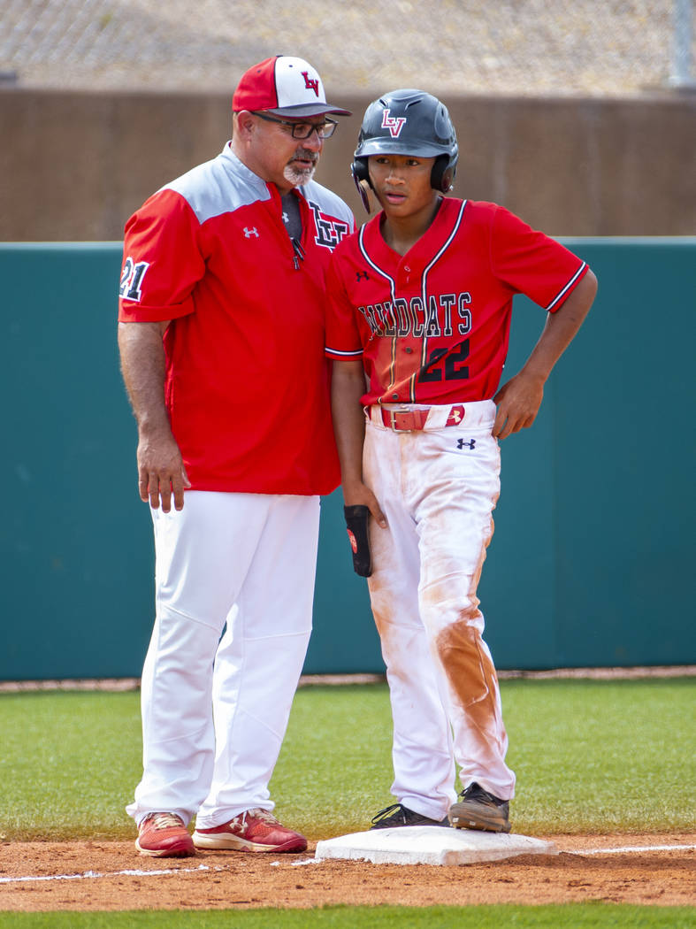 Longtime Las Vegas High coach Sam Thomas instructs runner Layne Adaro (22) at third base during ...