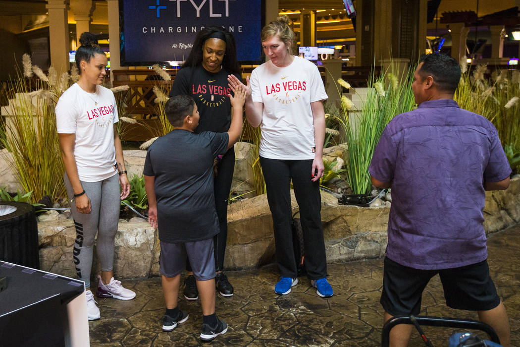 Braeden Sada, 11, high-fives Las Vegas Aces player Carolyn Swords, right, as players Kayla McBr ...