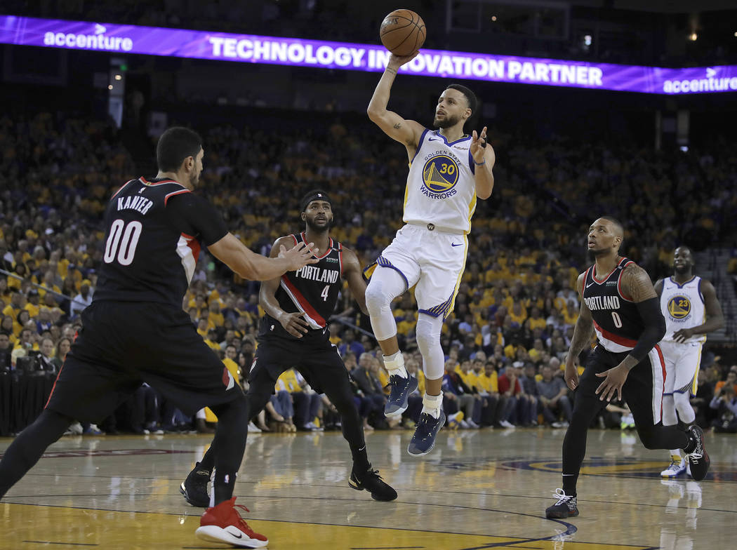 Golden State Warriors' Stephen Curry (30) shoots between Portland Trail Blazers' Maurice Harkle ...
