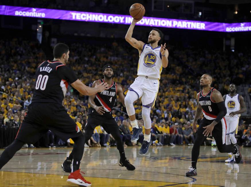 Golden State Warriors' Stephen Curry (30) shoots between Portland Trail Blazers' Maurice Harkle ...