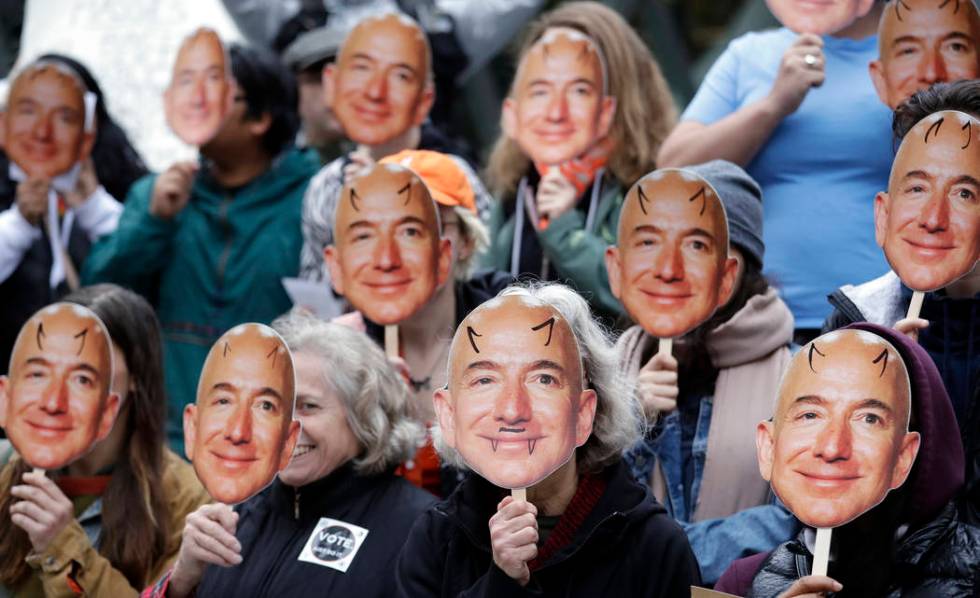 FILE - In this Oct. 31, 2018, file photo, demonstrators hold images of Amazon CEO Jeff Bezos ne ...