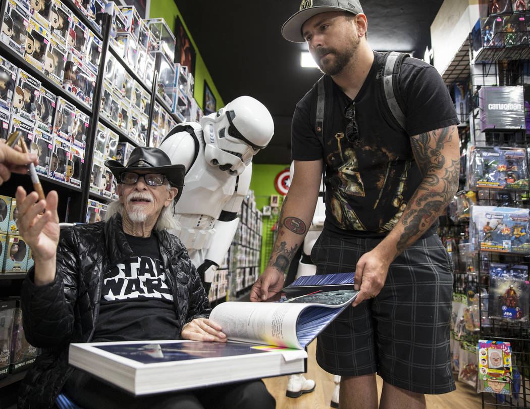 Colin Cantwell, left, concept artist and model builder for the original Star Wars movies, signs ...