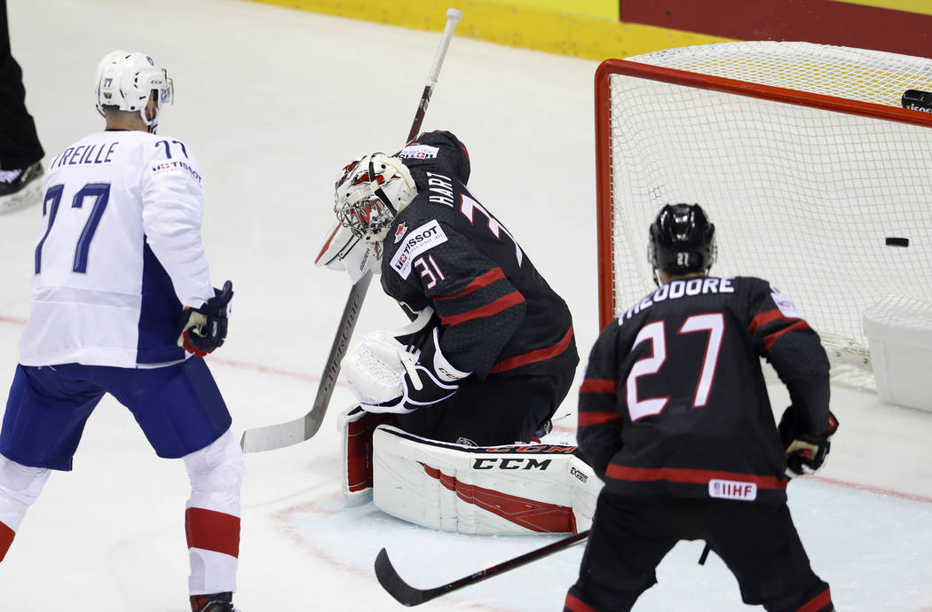 Canada's Shea Theodore, right, and Sacha Treille of France, left, watch as Canada's goaltender ...