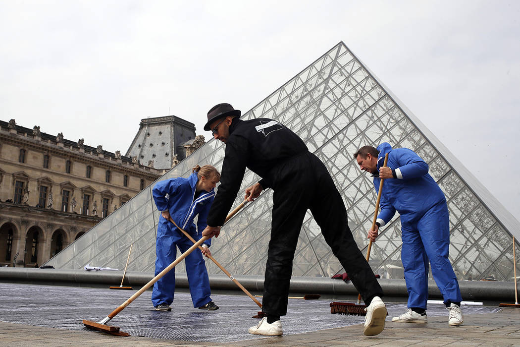 French street artist JR works in the courtyard of the Louvre Museum near the glass pyramid desi ...