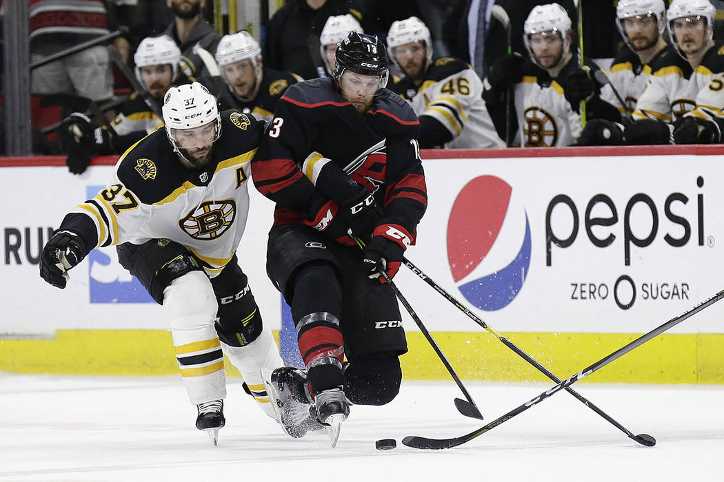 Boston Bruins' Patrice Bergeron (37) reaches in on Carolina Hurricanes' Warren Foegele (13) dur ...