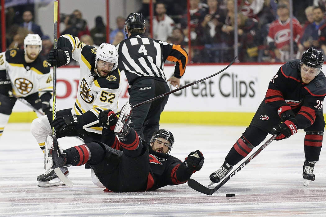 Boston Bruins' Sean Kuraly (52) and Carolina Hurricanes' Greg McKegg struggle during a face-off ...