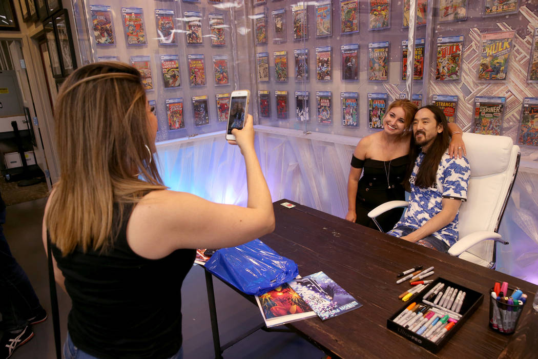DJ Steve Aoki poses with Savannah Ward as Ada Fino takes a photo during a signing for his new c ...
