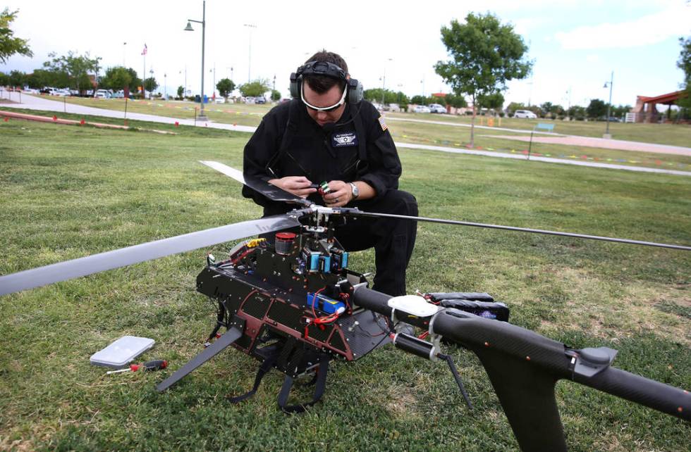 Jason Daub, a pilot in command, inspects before flying the Vapor 55 unmanned helicopter over Cr ...