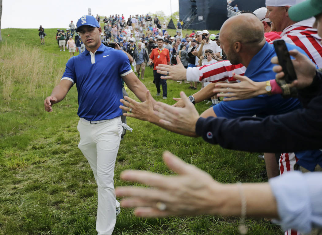 Brooks Koepka greets spectators as he walks down to the 15th tee during the second round of the ...