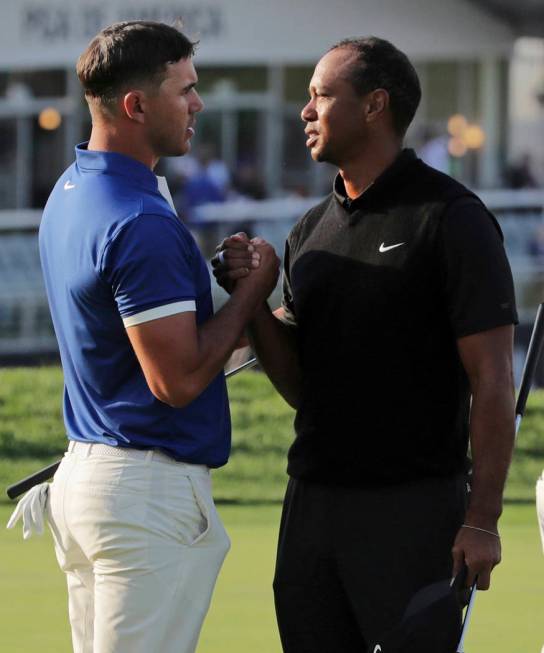 Brooks Koepka, left, shakes hands with Tiger Woods after finishing the second round of the PGA ...