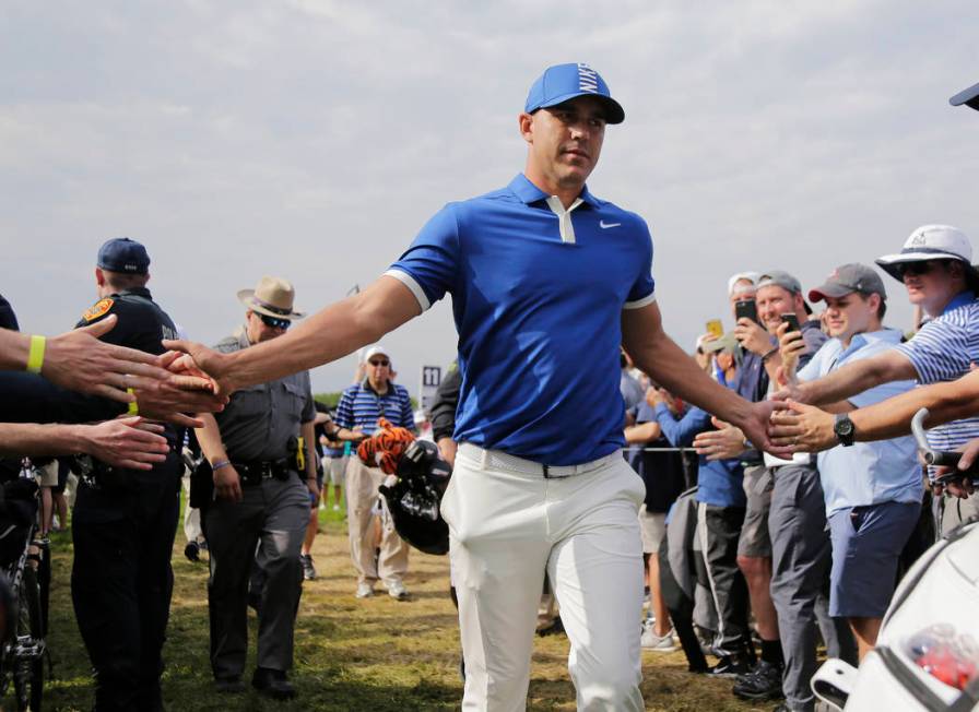 Brooks Koepka greets spectators as he walks to the 12th tee during the second round of the PGA ...