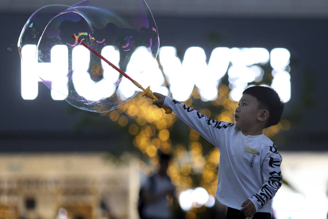 In this photo taken Monday, May 20, 2019, a child plays with bubbles near the logo for tech gia ...