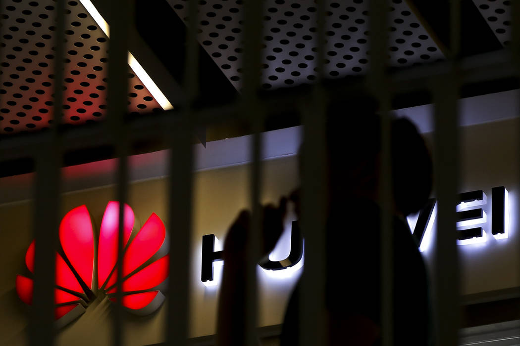 A man walks by a Huawei retail shop behind a handrail inside a commercial office building in Be ...