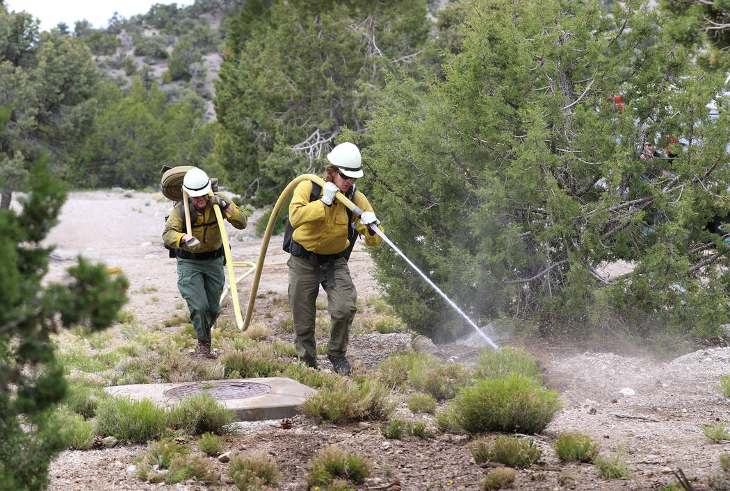 Firefighter from Bureau of Land Management Calvin Goff, front, and Travis Flowers spray water a ...