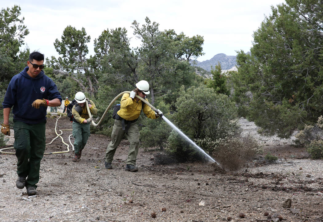 Firefighter from Bureau of Land Management, Calvin Goff, right, and Travis Flowers, center, spr ...