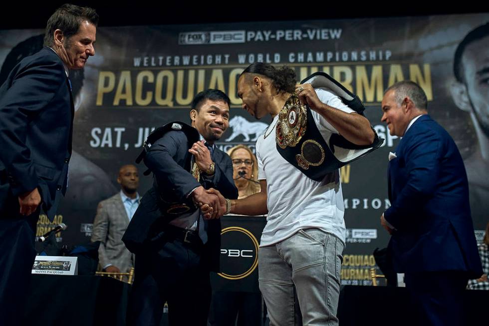 Manny Pacquiao, center left, shakes hands with Keith Thurman, center right, during a news confe ...