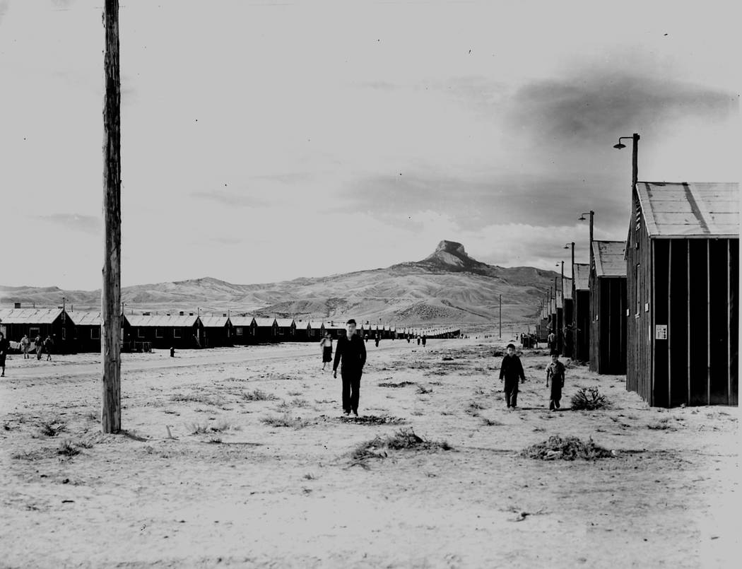 Three men are seen standing outside the barracks at the internment camp near Heart Mountain in ...