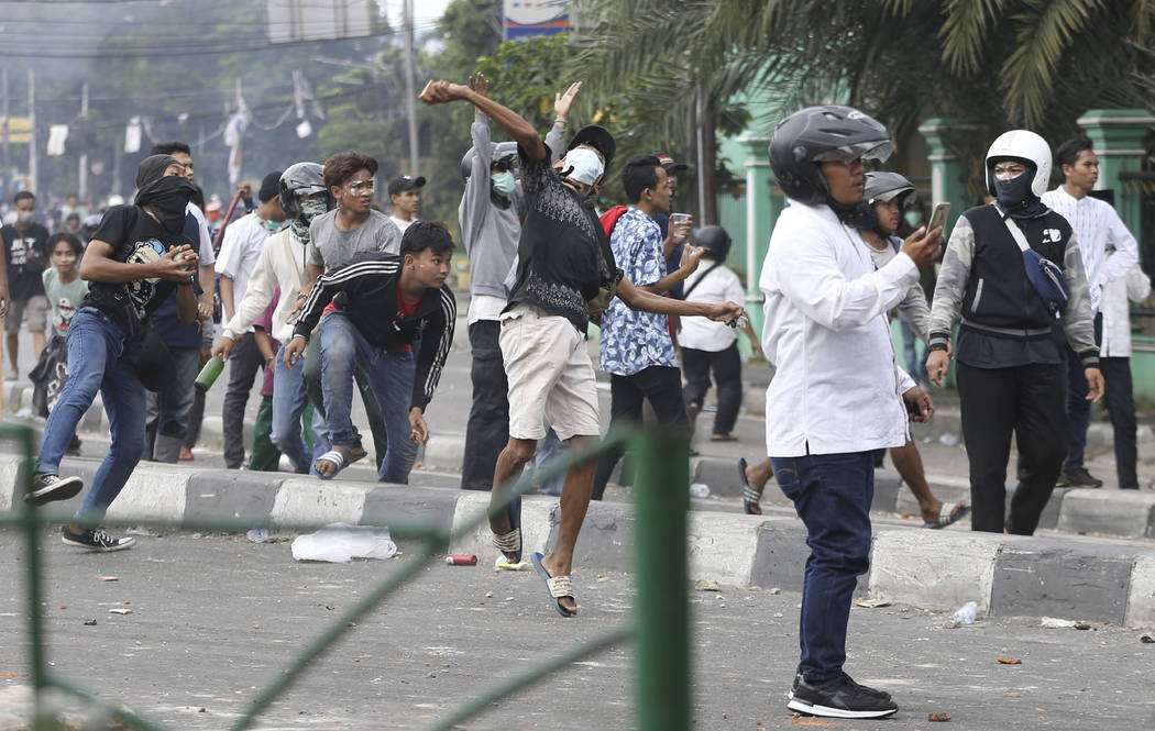Supporters of the losing presidential candidate throw rocks at police Wednesday, May 22, 2019, ...