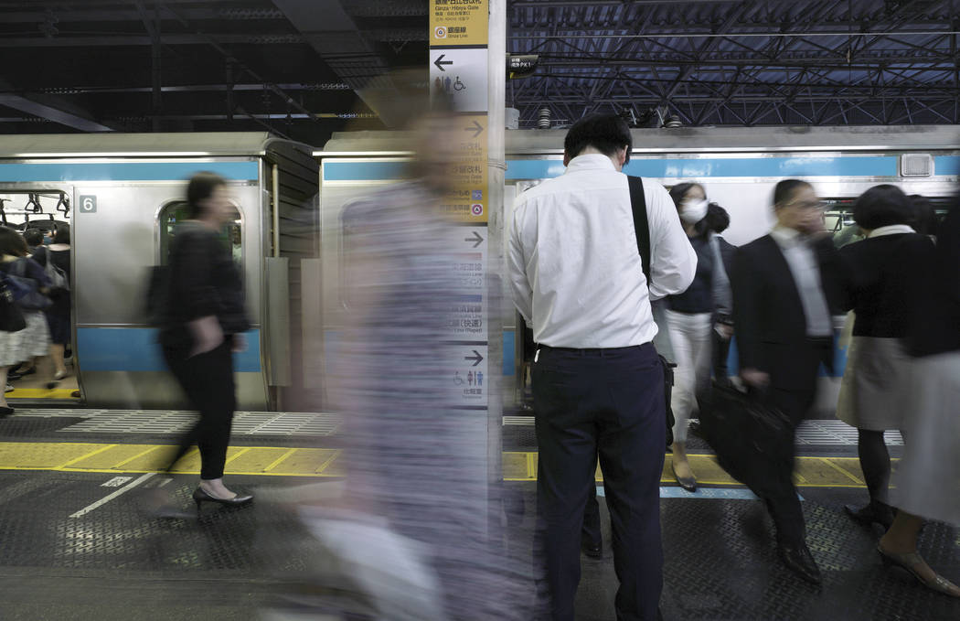 Commuters get on and off a train at a station Wednesday, May 22, 2019, in Tokyo. A police-devel ...