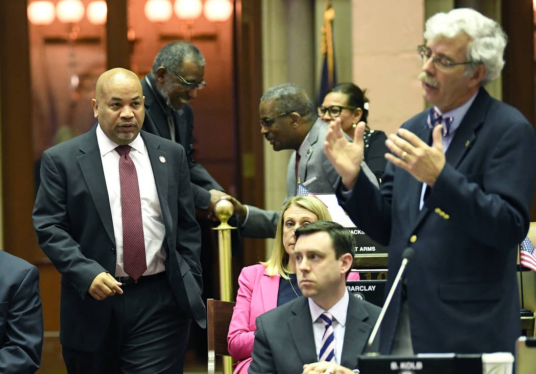 Assembly Speaker Carl Heastie, D-Bronx, left, walks on the Assembly floor as Assemblyman Andy G ...