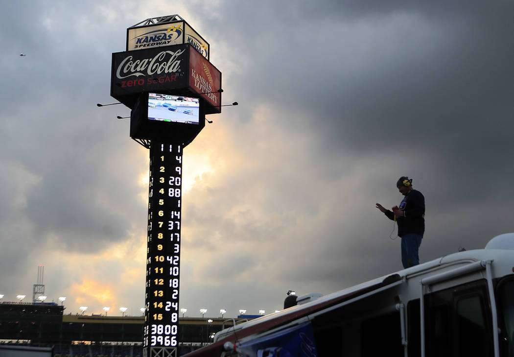 A fan follows events from the roof of a camper during the NASCAR Cup Series auto race at Kansas ...