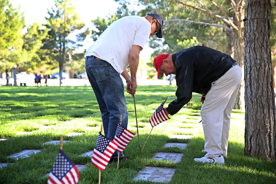 Volunteers William Wasserburger, left, and Ray Pelletier, U.S. Army veteran, place an American ...