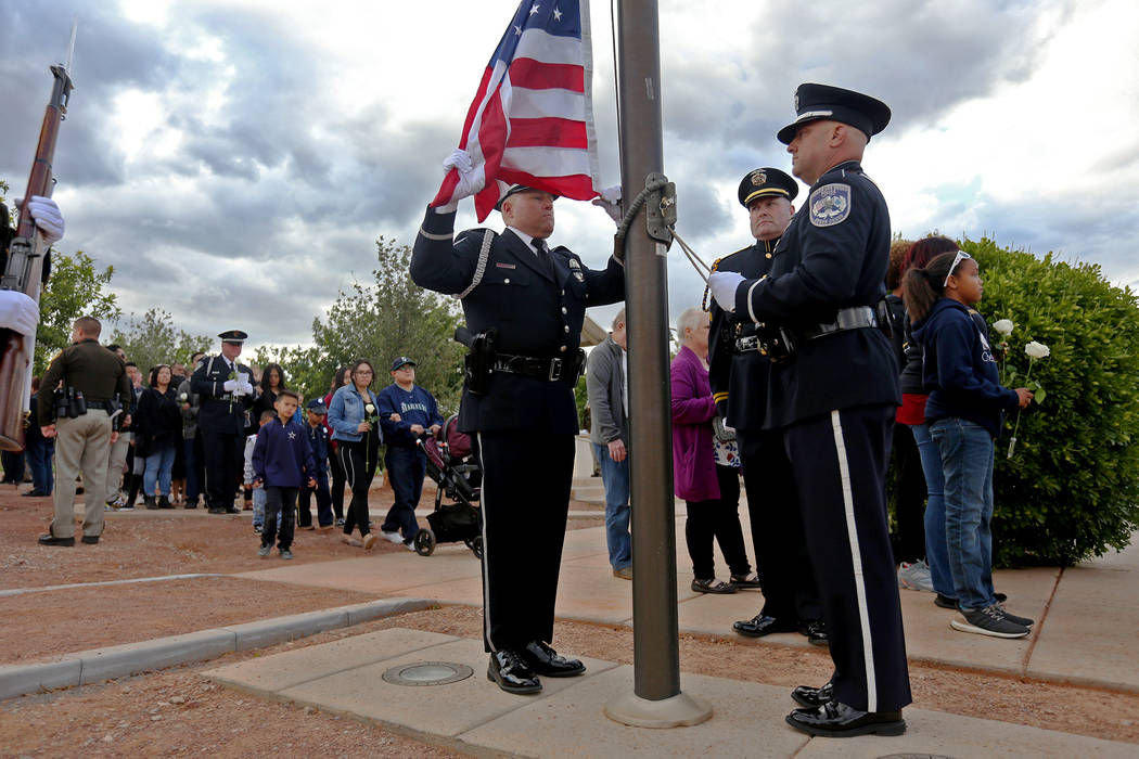 The color guard prepare to lift the flag to half mast as families of fallen officers walk behin ...