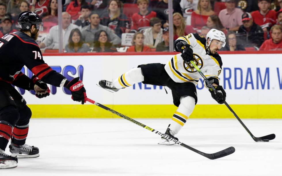 Boston Bruins' Brad Marchand (63) takes a shot on goal while Carolina Hurricanes' Jaccob Slavin ...