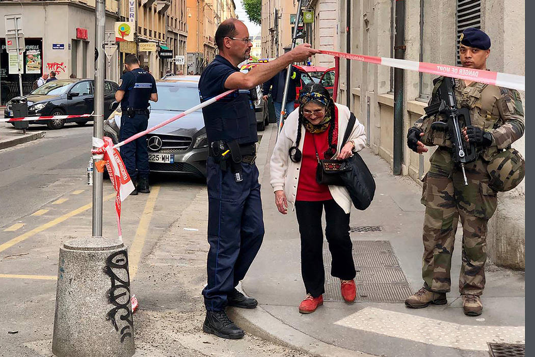 A police officer lets an elderly woman leaving the area while soldiers secure the access near t ...