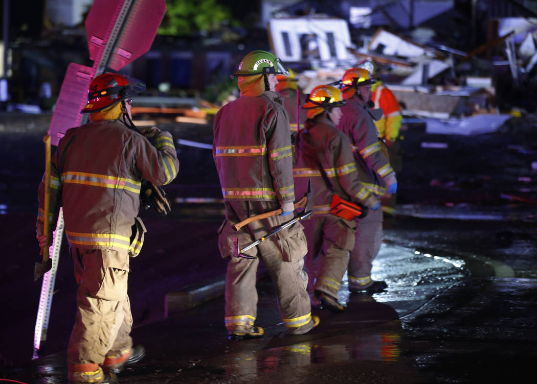 Firefighters walk to an area of debris from a hotel and a mobile home park in El Reno, Okla., S ...