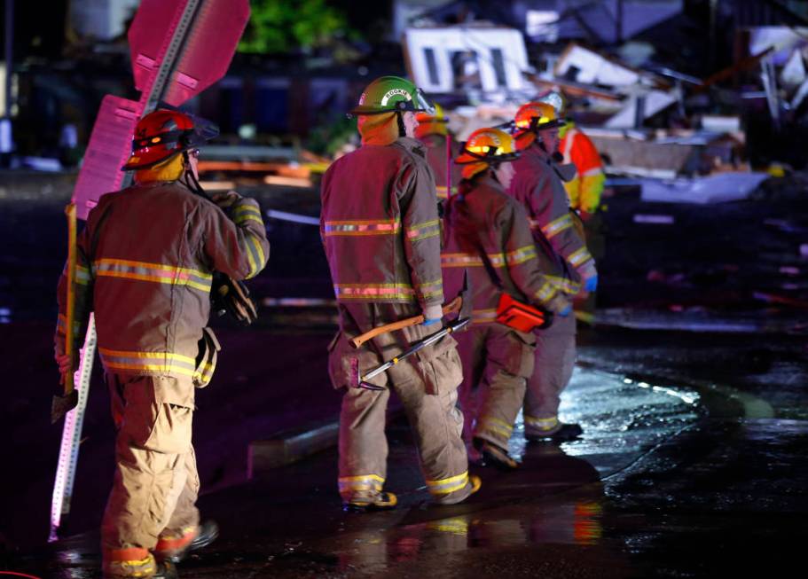 Firefighters walk to an area of debris from a hotel and a mobile home park in El Reno, Okla., S ...