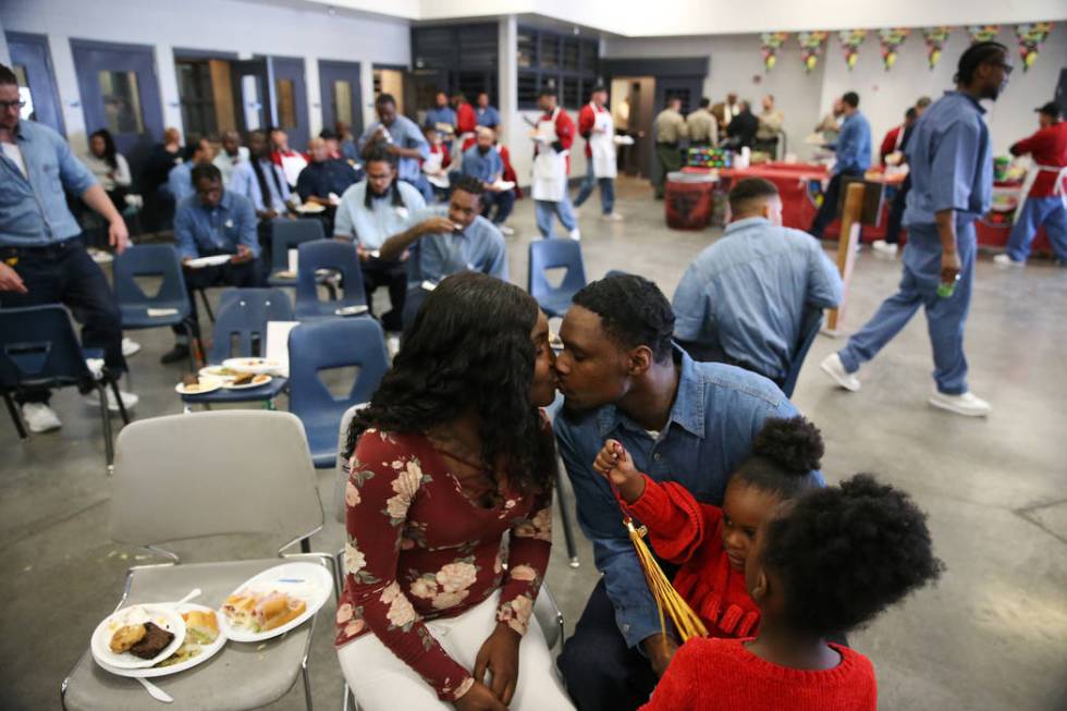 Inmate Daysean Jenkins, second from left, kisses his fiancée Tasianna Caver, with his daug ...