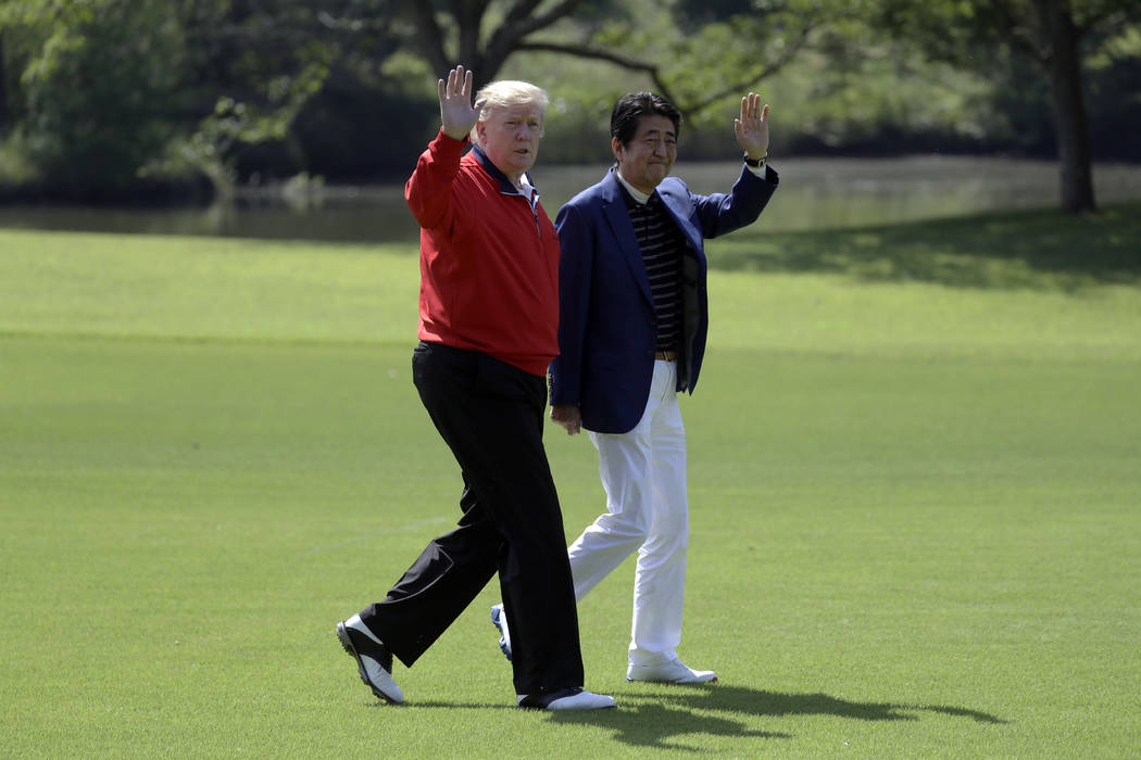 President Donald Trump walks with Japanese Prime Minister Shinzo Abe before playing a round of ...