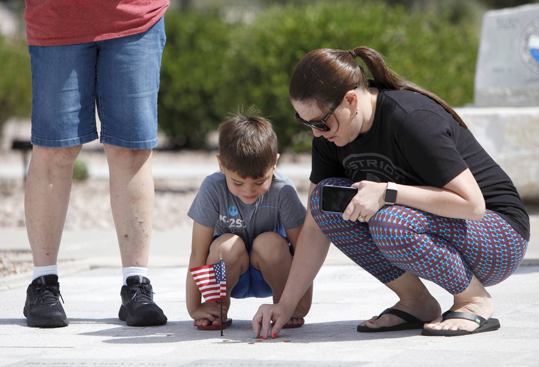 Sarah Vela helps her son Jace Vela, 5, place a flag on her grandfatherճ memorial stone at ...