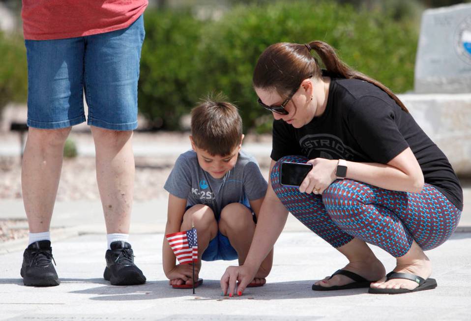 Sarah Vela helps her son Jace Vela, 5, place a flag on her grandfatherճ memorial stone at ...