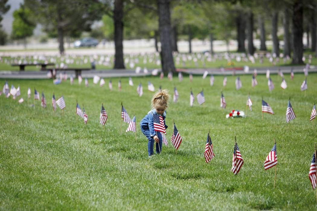 Liyah Makarechian, 3, places a flag at a headstone site at the Southern Nevada Veterans Memoria ...