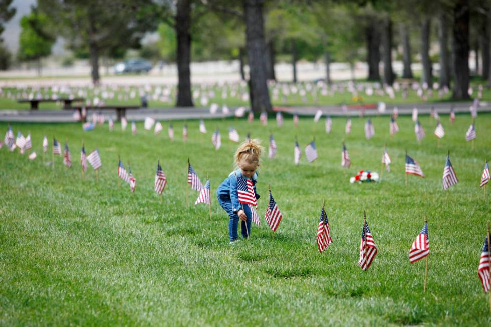 Liyah Makarechian, 3, places a flag at a headstone site at the Southern Nevada Veterans Memoria ...