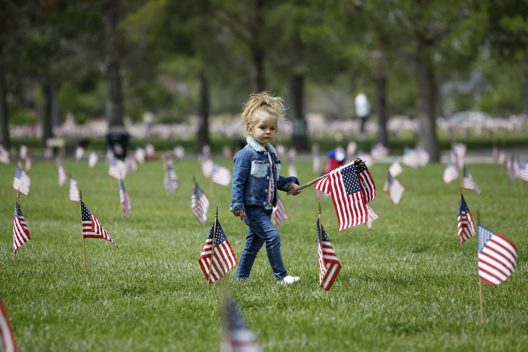 Liyah Makarechian, 3, wanders with a flag at the Southern Nevada Veterans Memorial Cemetery in ...