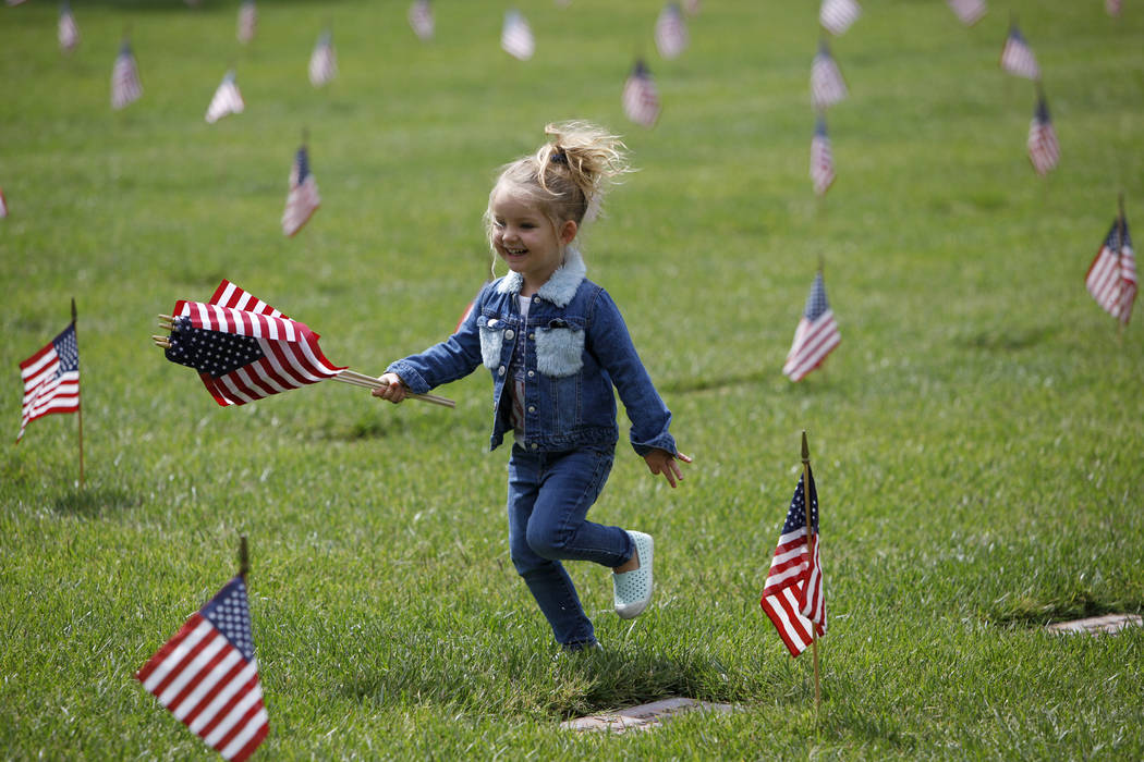 Liyah Makarechian, 3, runs with a flag at the Southern Nevada Veterans Memorial Cemetery in Bou ...