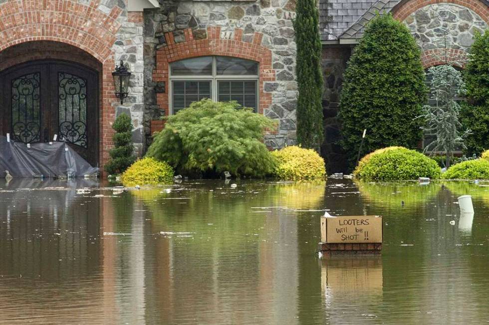 A sign reading "Looters will be shot!!" sits in front of a flooded home on Turtle Bay ...