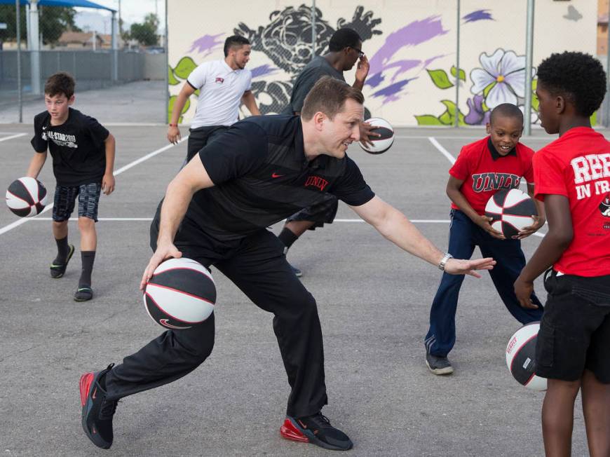 UNLV head basketball coach T.J. Otzelberger, center, dribbles through a crowd of kids during a ...