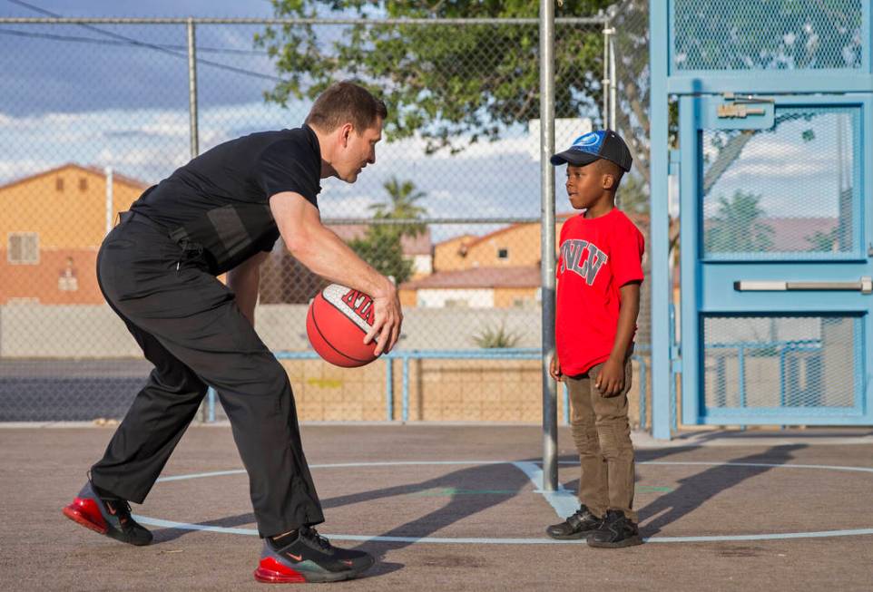 UNLV head basketball coach T.J. Otzelberger, left, teaches Devori Brown, 6, how to dribble duri ...